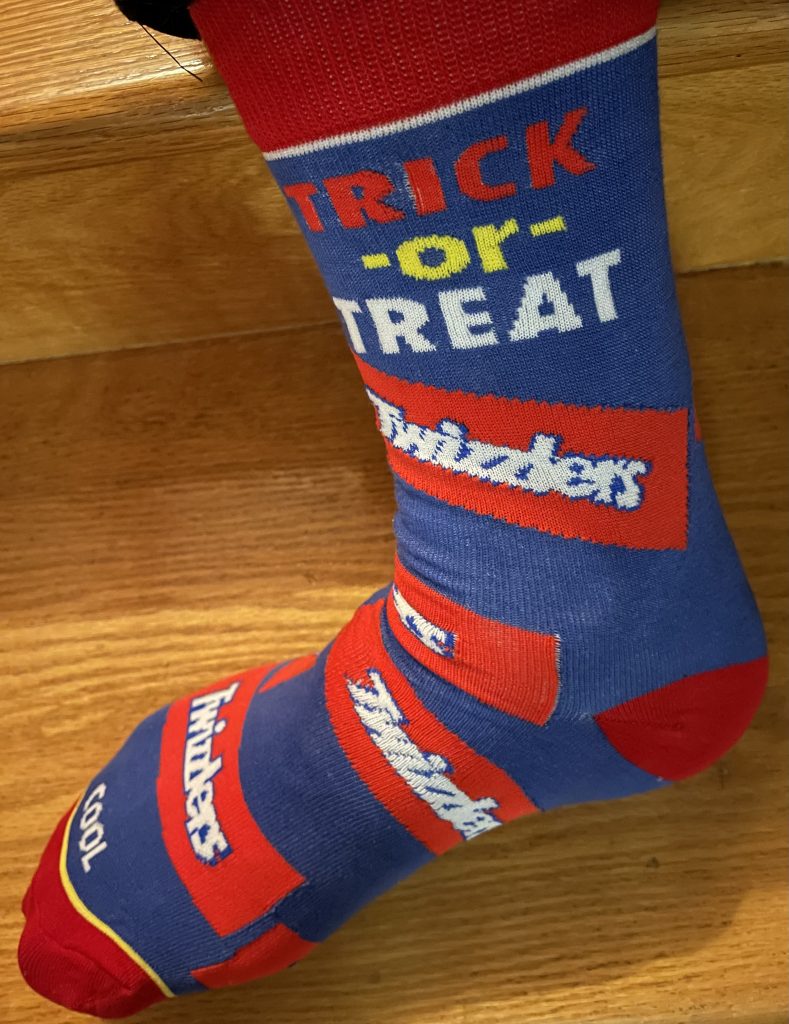 Me wearing a sock with Trick or Treat on it, with several Twizzler images along the length of it.